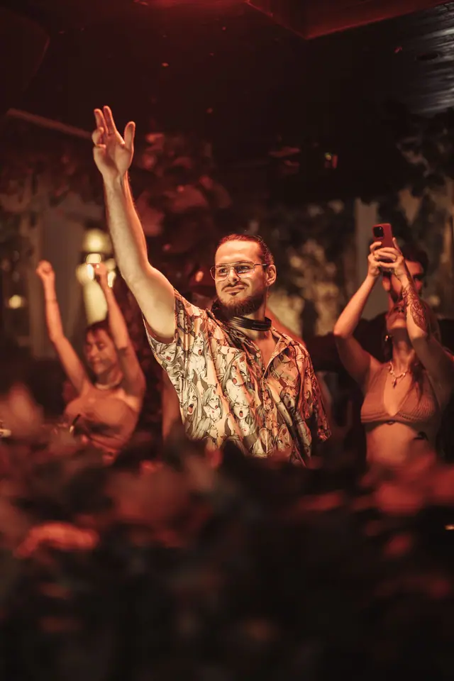 OPPAACHA with both arms raised in front of a dancing crowd
