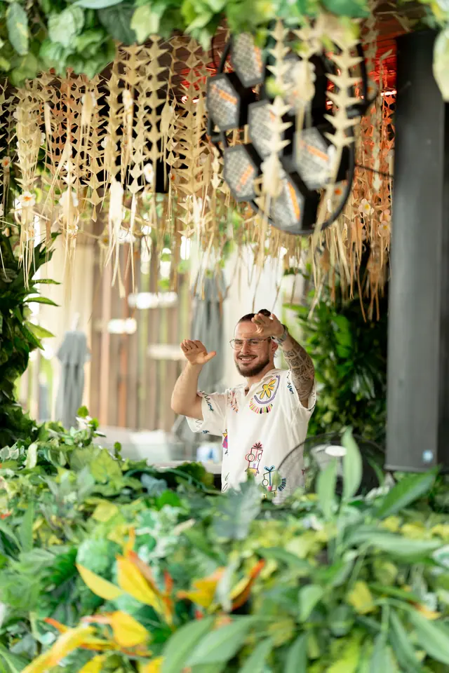 OPPAACHA playing a daytime set framed by tropical plants and woven decor